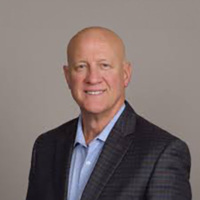 Darrell Pattillo smiling in a professional headshot with a blazer and light blue shirt.